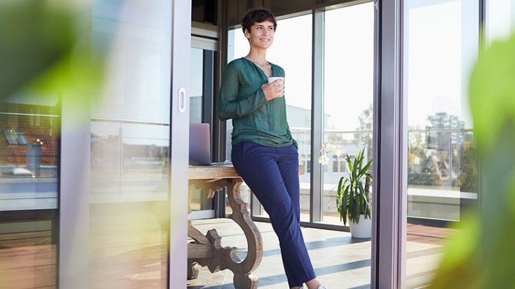 Smiling businesswoman leaning against table having a coffee break