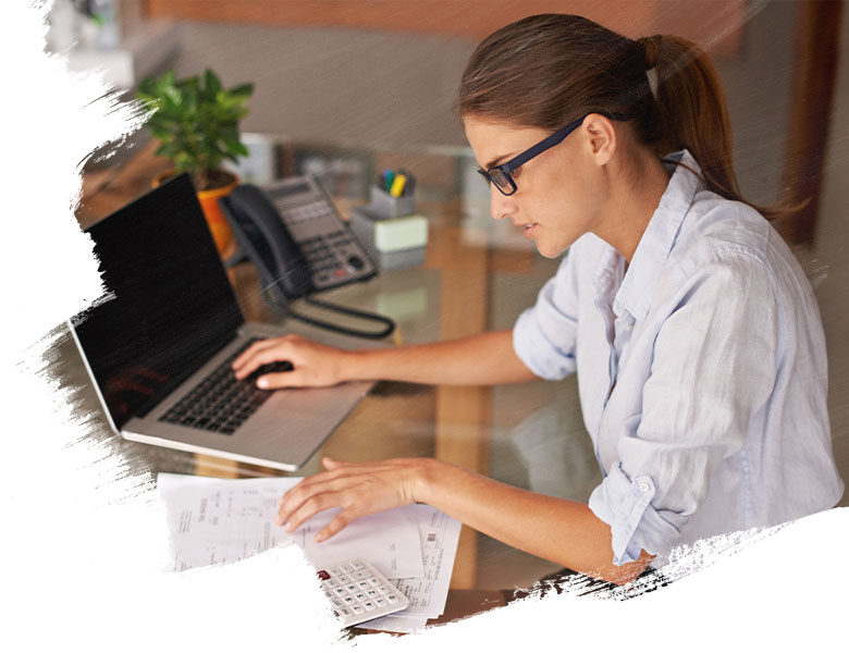 Businesswoman diligently working at her office desk, meticulously reviewing financial documents and receipts while using laptop.