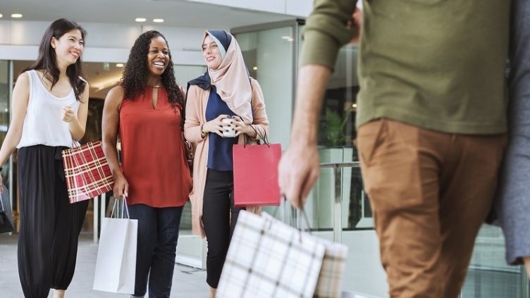 women coming out of a retail store carrying lots of shopping bags