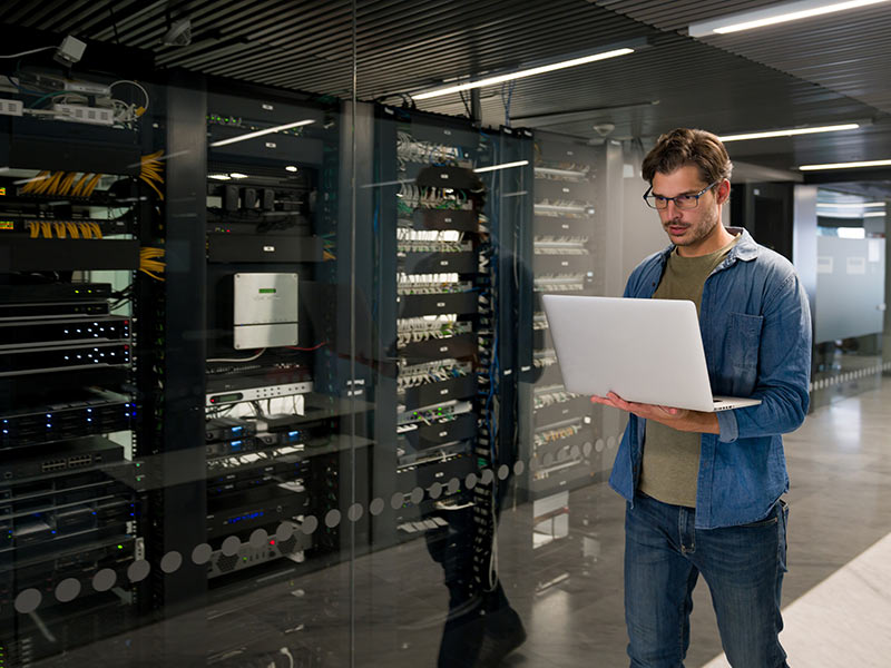 A person using laptop in a server room