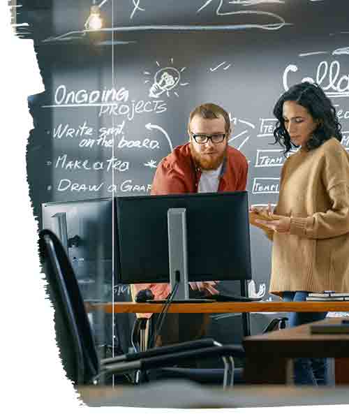 2 Office space designers discussing location strategy(Computer in front of them and blackboard in background)